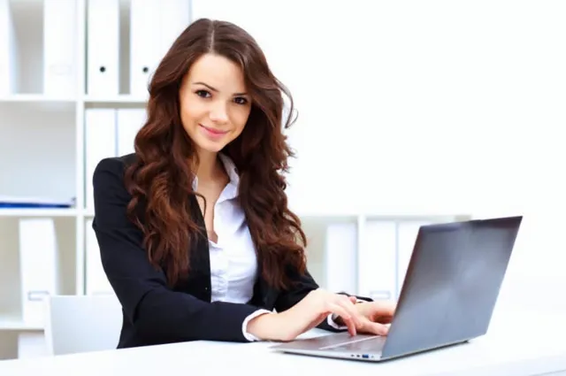 A dental practice administrator working at a laptop in a bright office